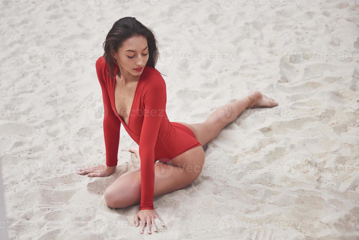 bella giovane donna abbronzata in bikini rosso in posa sulla spiaggia. ritratto modello sexy con un corpo perfetto. concetto di vacanza estiva foto