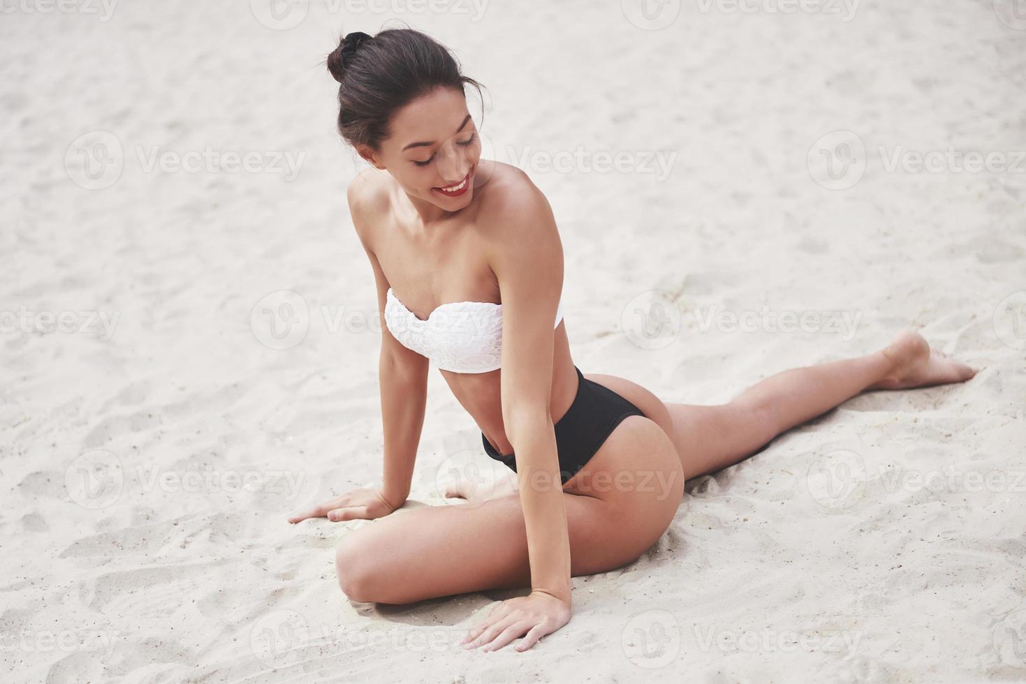 bella ragazza di lusso sottile in bikini sulla spiaggia di sabbia su un'isola tropicale. corpo abbronzato sexy e figura perfetta foto