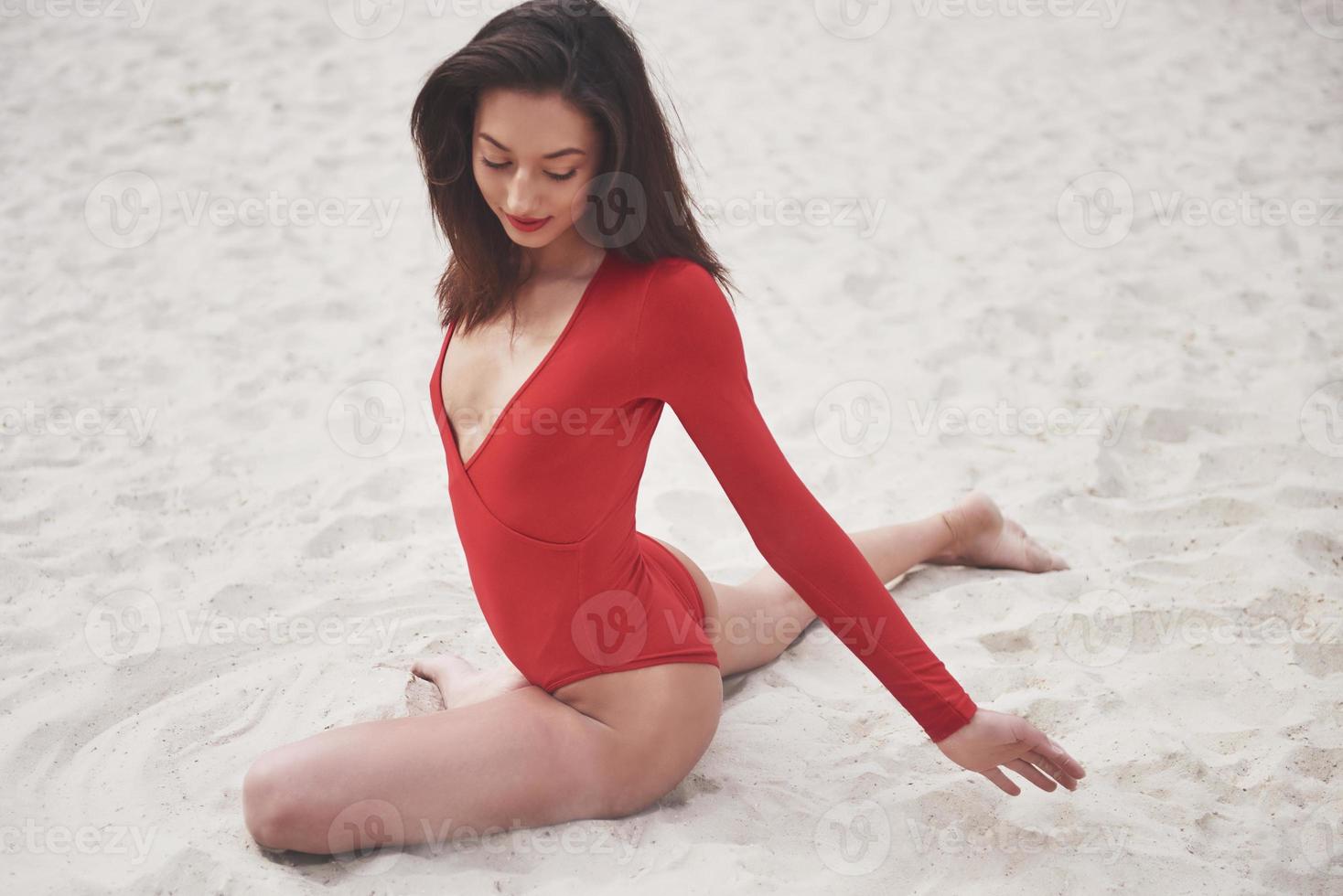 bella giovane donna abbronzata in bikini rosso in posa sulla spiaggia. ritratto modello sexy con un corpo perfetto. concetto di vacanza estiva foto