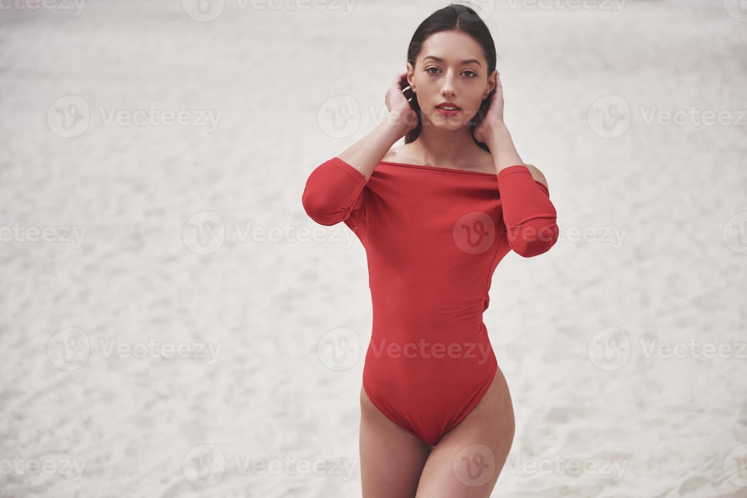 bella giovane donna abbronzata in bikini rosso in posa sulla spiaggia. ritratto modello sexy con un corpo perfetto. concetto di vacanza estiva foto