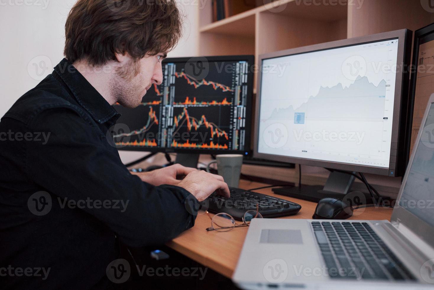 giornata stressante in ufficio. giovane uomo d'affari che si tiene per mano sul viso mentre è seduto alla scrivania in ufficio creativo. concetto grafico di finanza forex trading di borsa foto