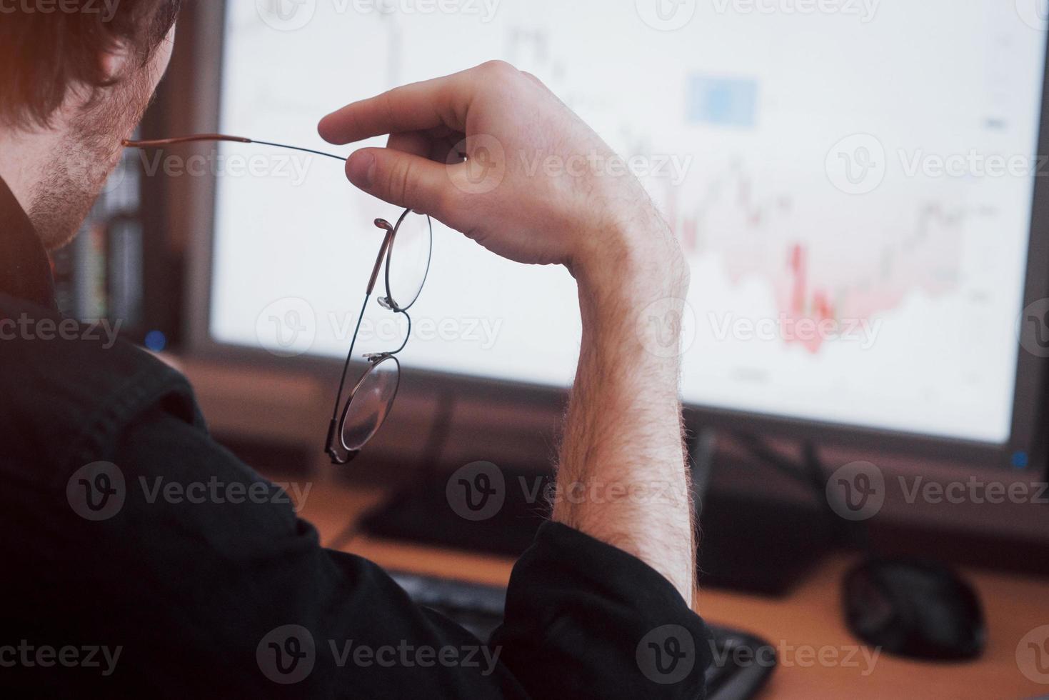 analizzare i dati. primo piano di un giovane uomo d'affari che tiene gli occhiali e guarda il gff mentre lavora in un ufficio creativo foto