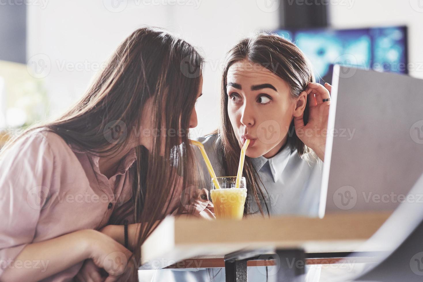 due bellissime gemelle trascorrono del tempo a bere succo di frutta. sorelle che si rilassano in un bar e si divertono insieme foto