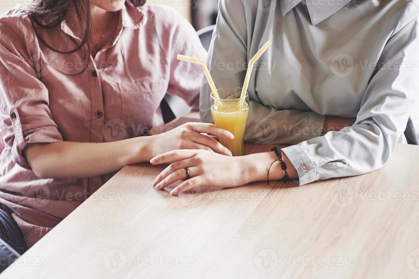 due bellissime gemelle trascorrono del tempo a bere succo di frutta. sorelle che si rilassano in un bar e si divertono insieme foto