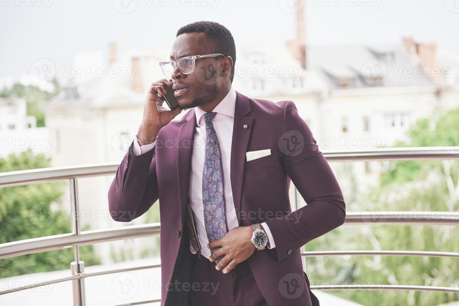 ritratto di un giovane e bello uomo d'affari afroamericano che parla al telefono in abito foto