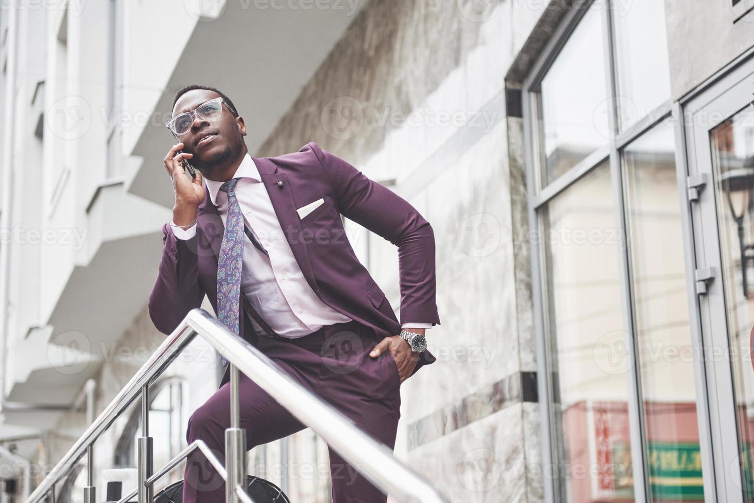 ritratto di un giovane e bel uomo d'affari afroamericano che parla al telefono in abito. preparando per un incontro di lavoro. foto