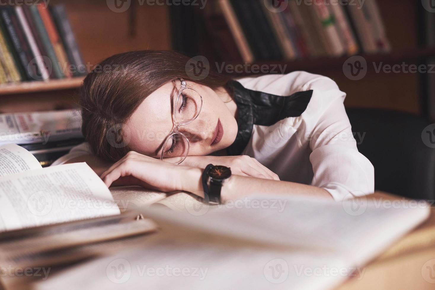 una giovane studentessa è stanca nella sala di lettura della vecchia biblioteca foto