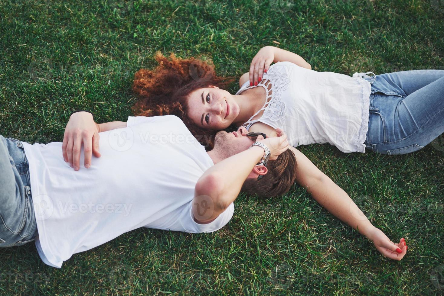 coppia romantica di giovani sdraiati sull'erba nel parco. sembrano felici. vista dall'alto. foto