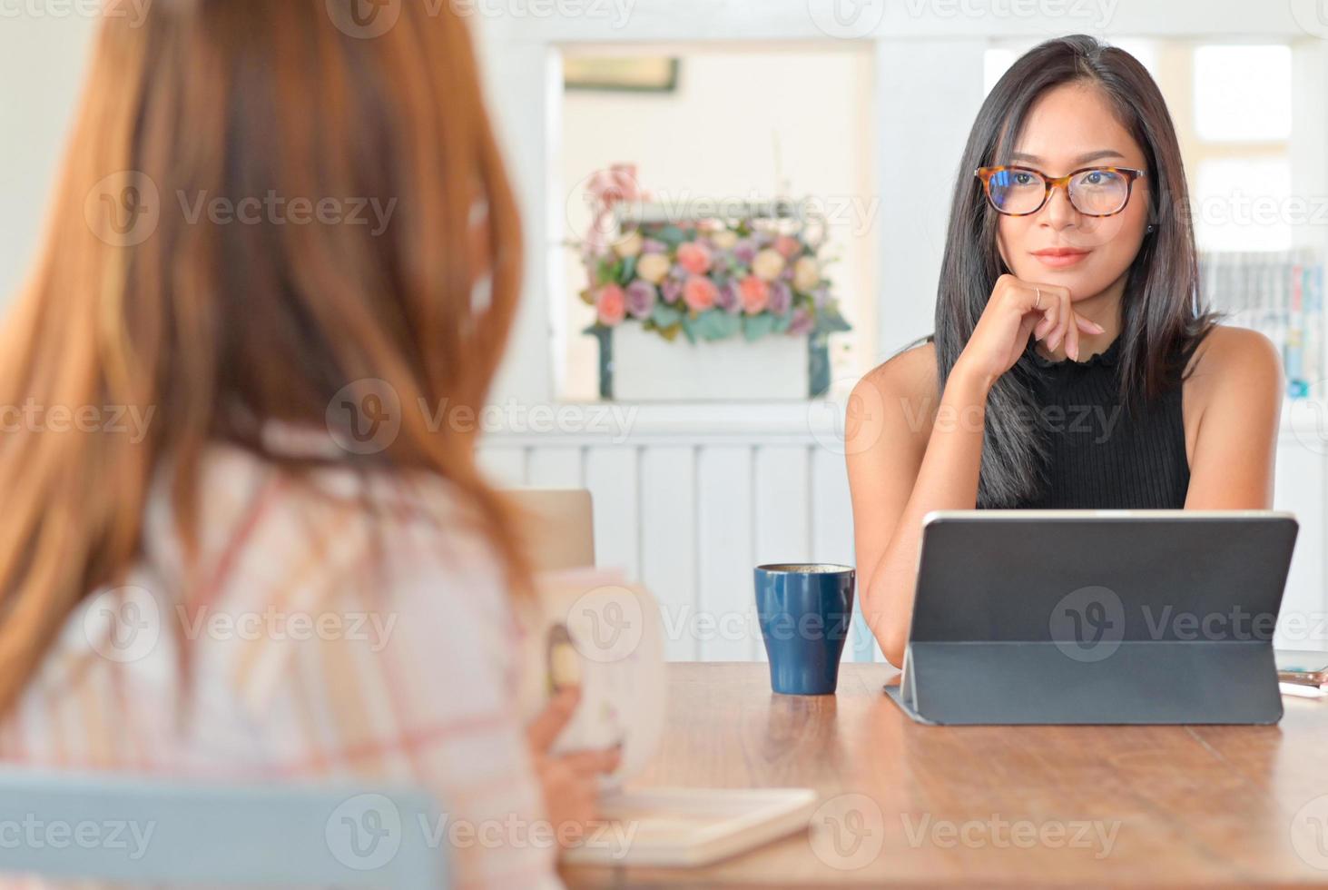 due giovani donne che parlano insieme a un tablet in soggiorno. si siedono distanziati per prevenire il virus. foto
