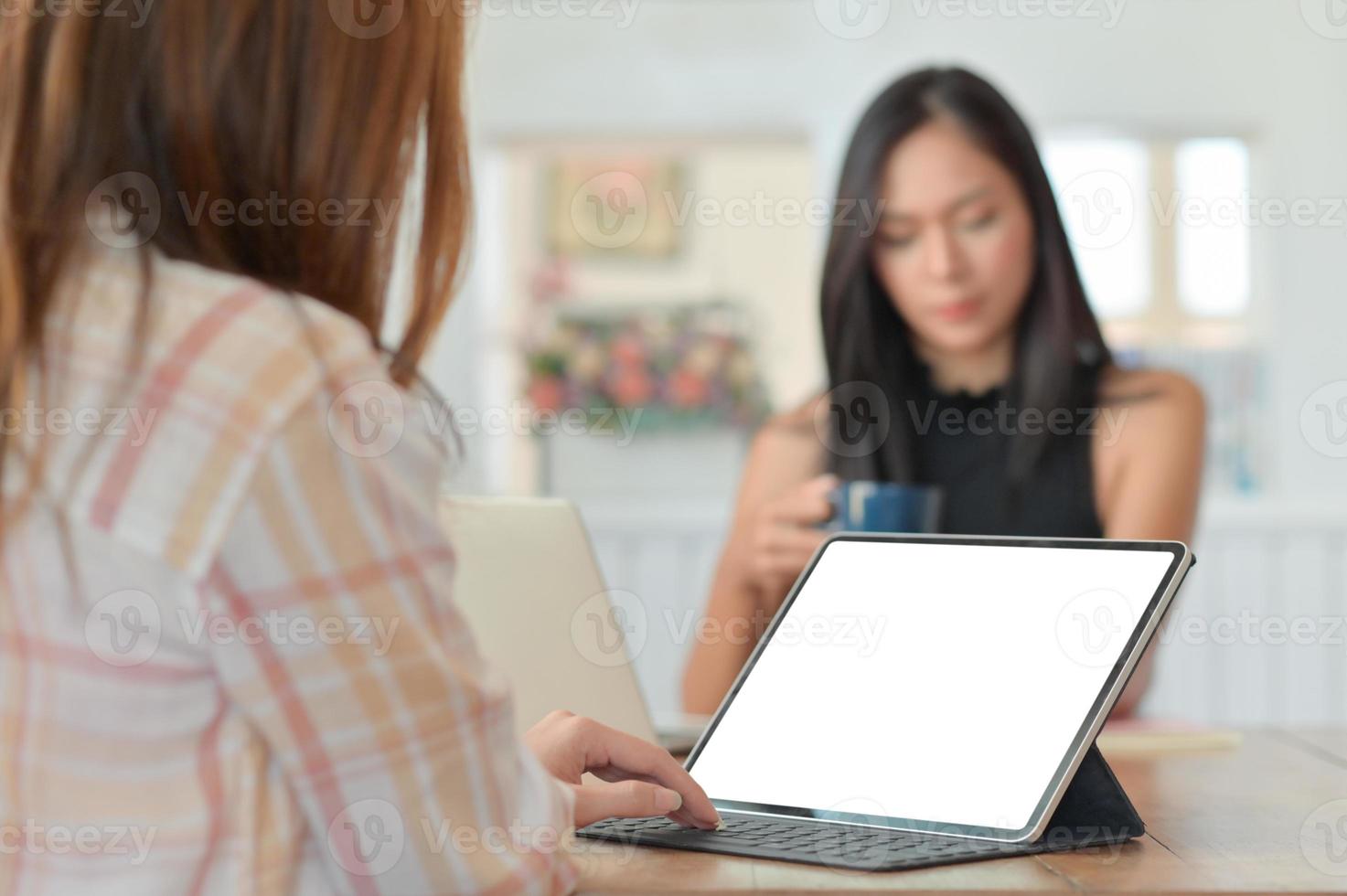 dipendente di sesso femminile che utilizza un laptop per presentare il progetto ai dirigenti seduti con il caffè nella parte posteriore. foto
