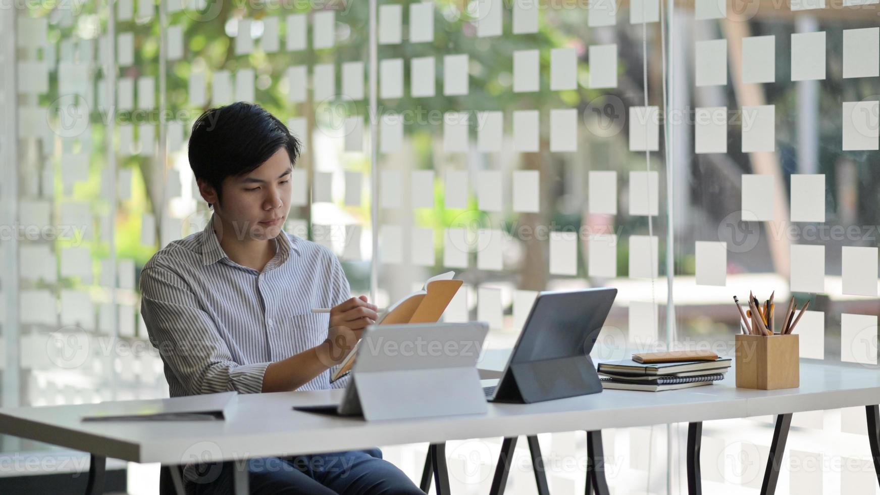 foto ritagliata di uno studente maschio asiatico con un laptop e un fermo che si prepara a completare la sua tesi per finire l'università.