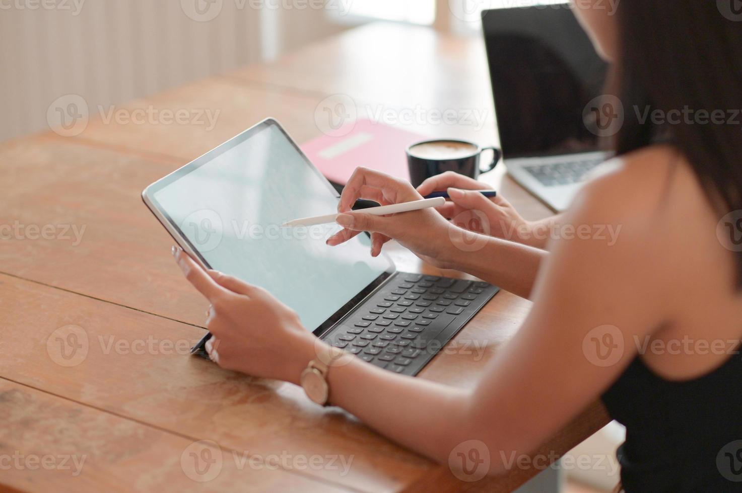 vista ritagliata di un giovane studente che usa una penna su un tablet per presentare la sua ammissione all'università. foto