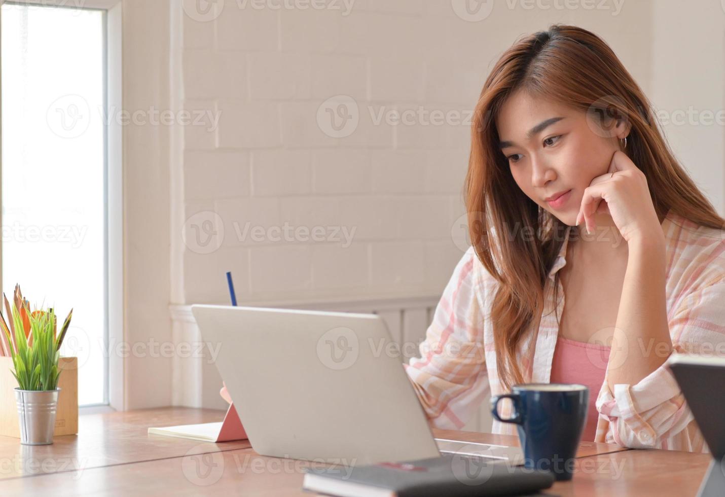 colpo ritagliato di studentessa adolescente sta studiando online a casa con un computer portatile. foto