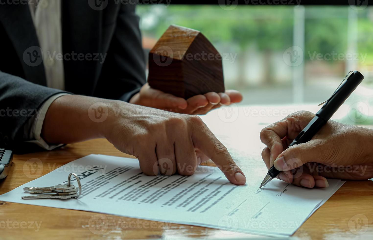 la mano del venditore indica al cliente di usare la penna per firmare il contratto. foto