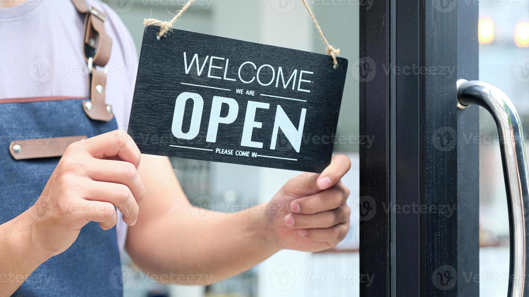 il personale sta appendendo cartelli aperti alla porta per aprire il servizio. foto