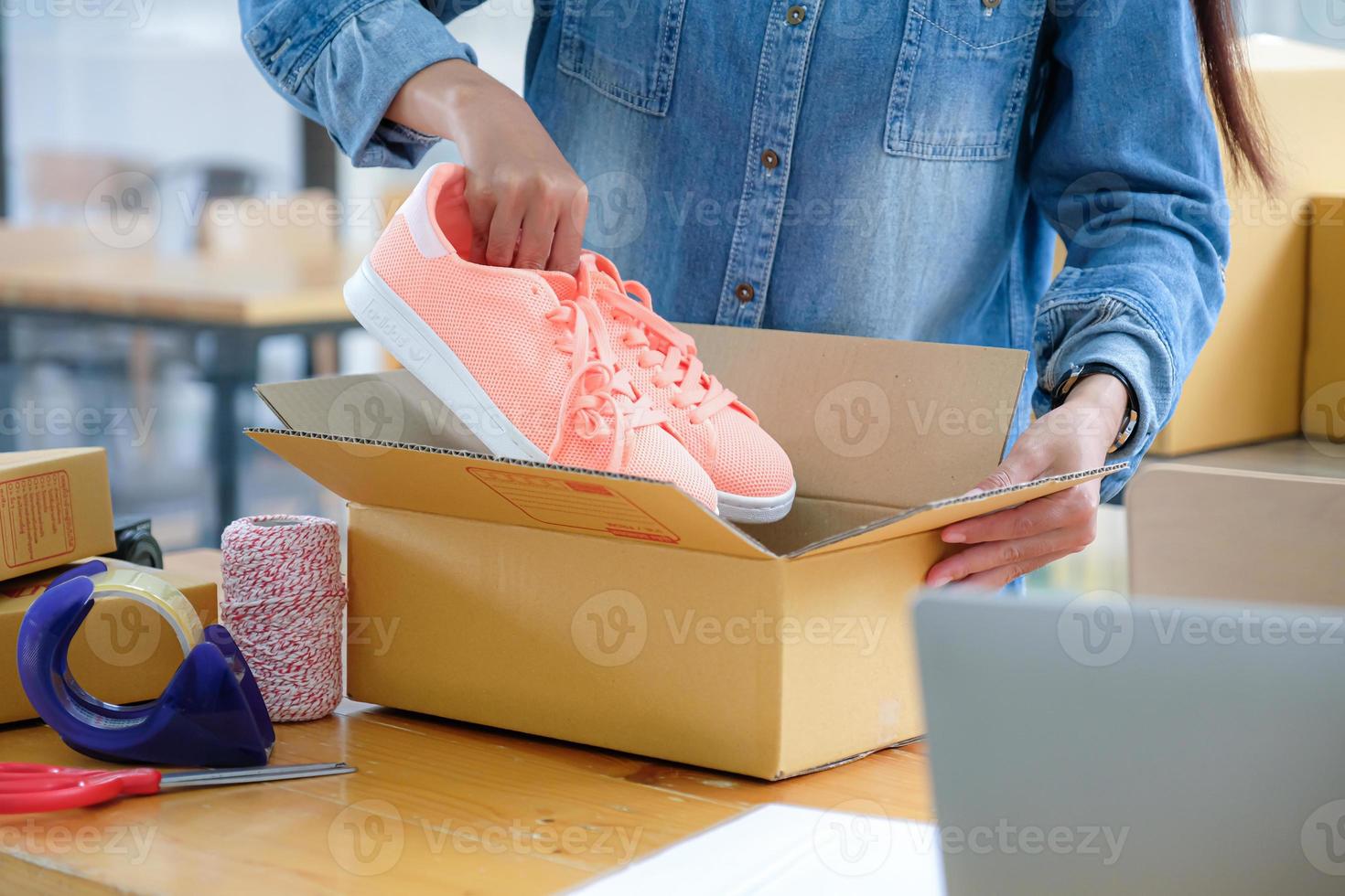 il personale addetto alla consegna dei pacchi sta imballando le scarpe rosa nella scatola per la consegna. foto