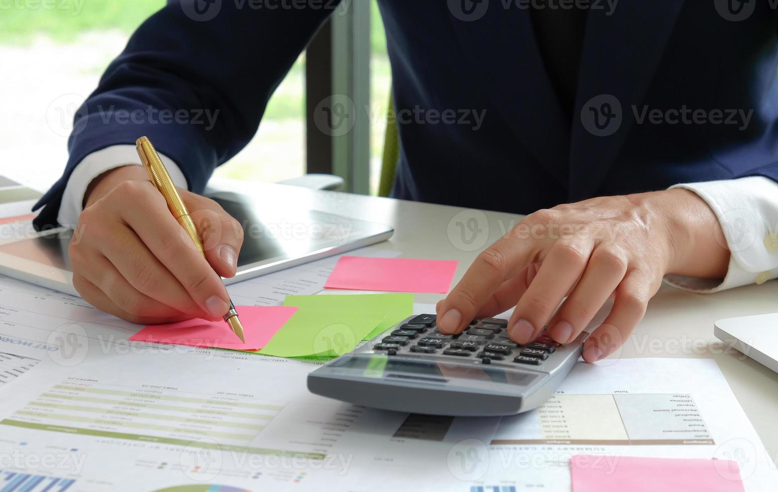 primo piano degli analisti utilizzano una calcolatrice e una penna per valutare la situazione fluttuante del mercato azionario. foto