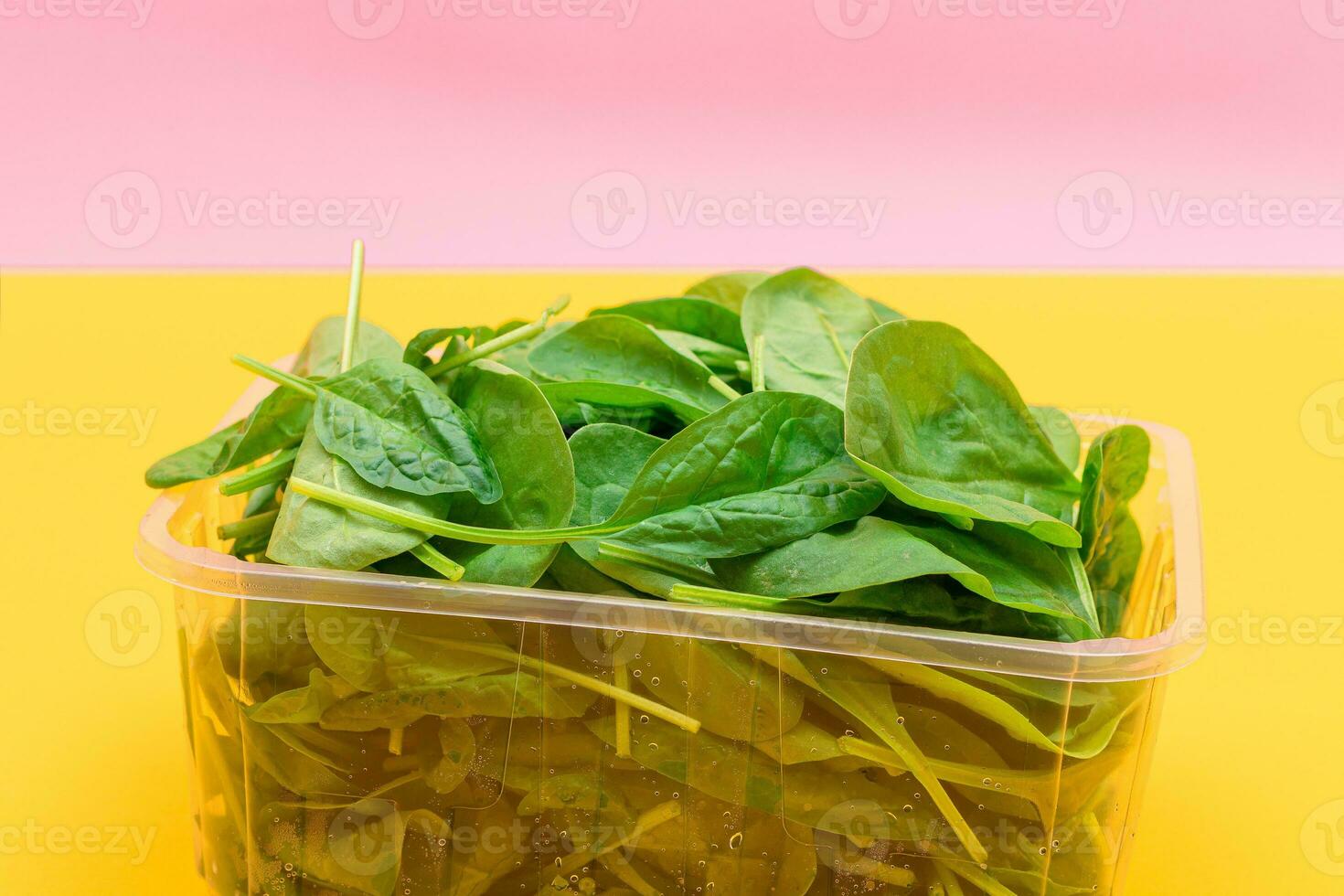 fresco bambino spinaci le foglie nel trasparente plastica pacchetto su giallo sfondo. vegano e vegetariano cultura. crudo cibo, verde le foglie. salutare dieta foto