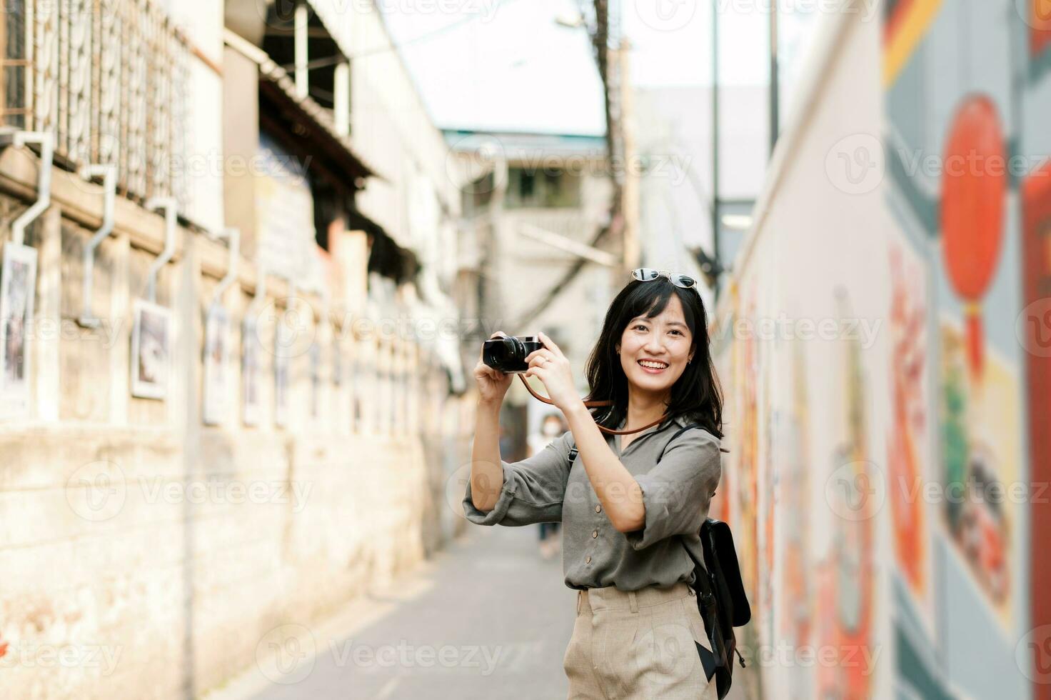 giovane asiatico donna zaino viaggiatore utilizzando digitale compatto telecamera, godendo strada culturale Locale posto e Sorridi. viaggiatore controllo su lato strade. foto