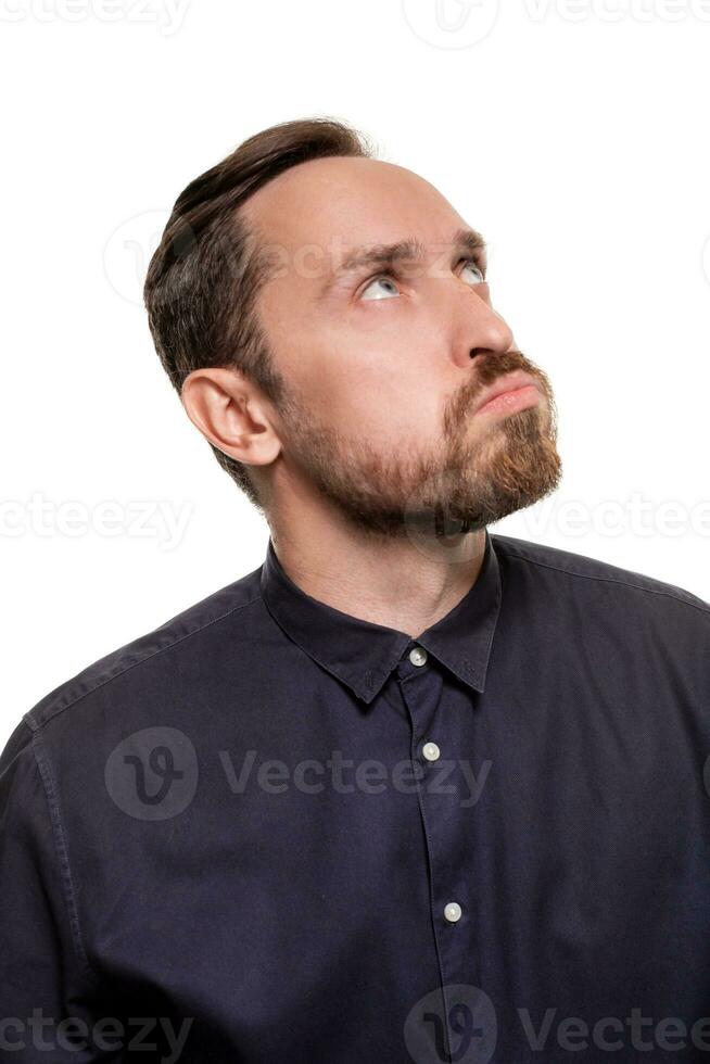 ritratto di un' bello, con la barba lunga uomo, vestito nel un' buio blu camicia, in piedi contro un' bianca sfondo. se stesso fiducioso uomo. foto