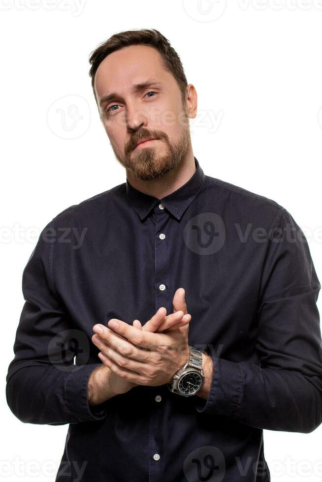 ritratto di un' bello, con la barba lunga uomo, vestito nel un' buio blu camicia, in piedi contro un' bianca sfondo. se stesso fiducioso uomo. foto