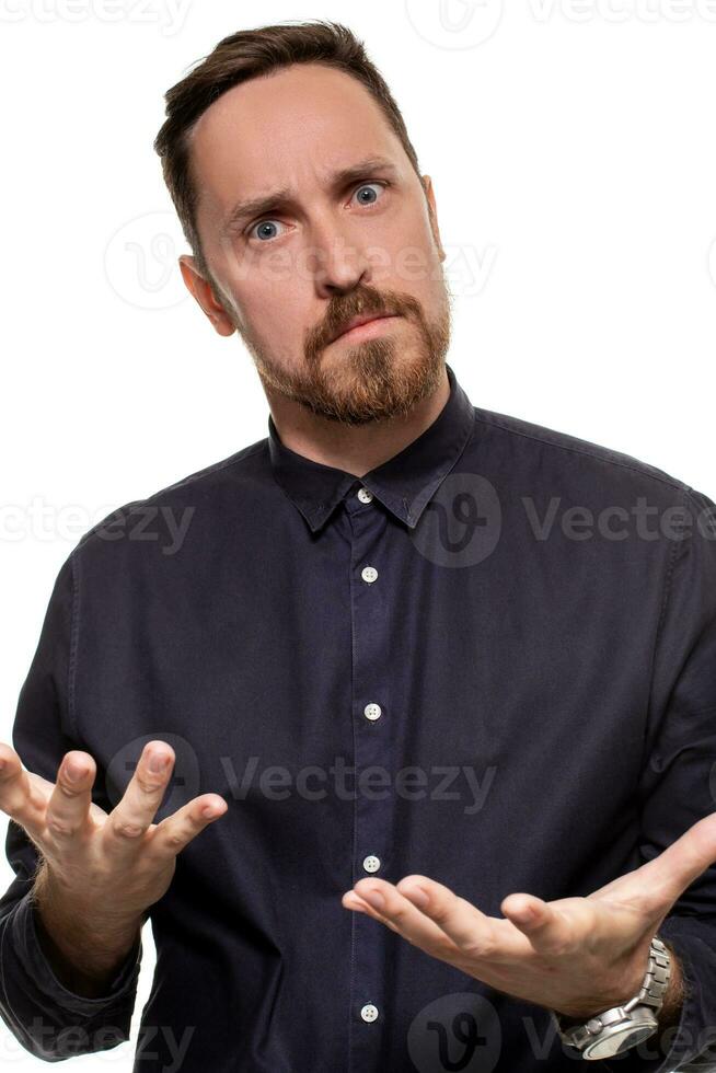 ritratto di un' bello, con la barba lunga uomo, vestito nel un' buio blu camicia, in piedi contro un' bianca sfondo. se stesso fiducioso uomo. foto