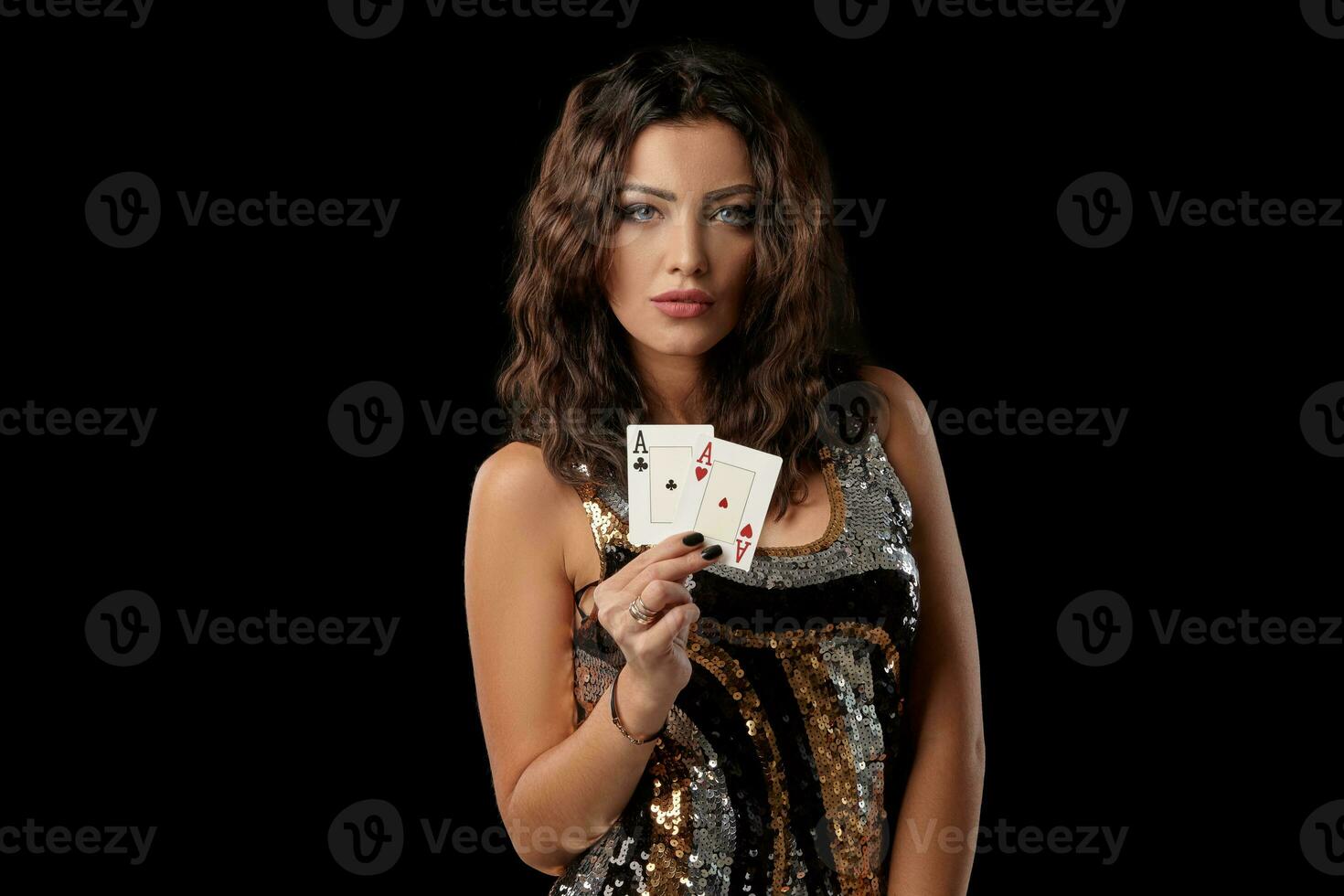 brunetta ragazza nel un' colorato lustrino vestito in posa Tenere Due giocando carte, in piedi contro nero studio sfondo. casinò, poker. avvicinamento. foto