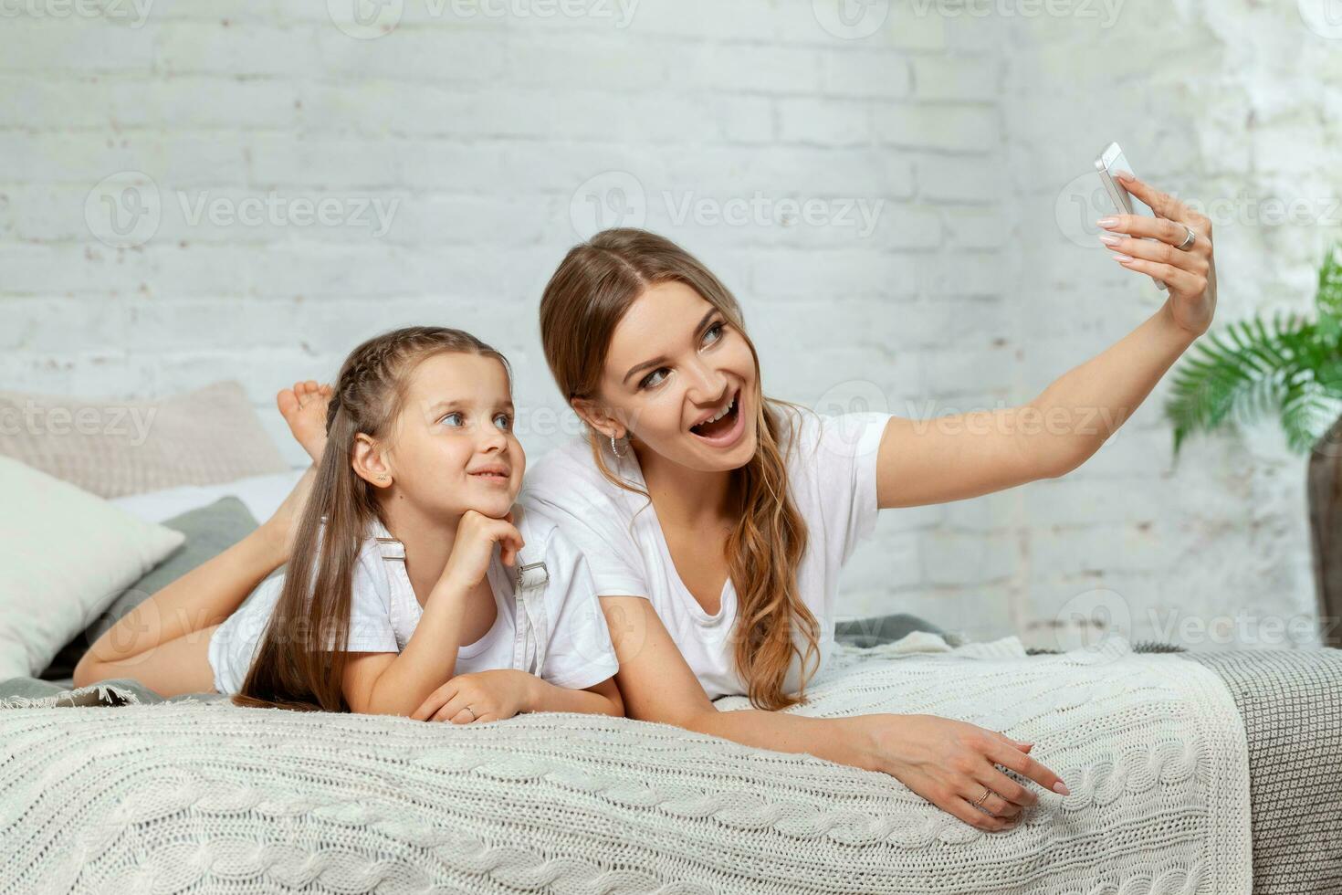 interno ritratto di un' bellissimo madre con sua affascinante poco figlia in posa contro Camera da letto interno. foto