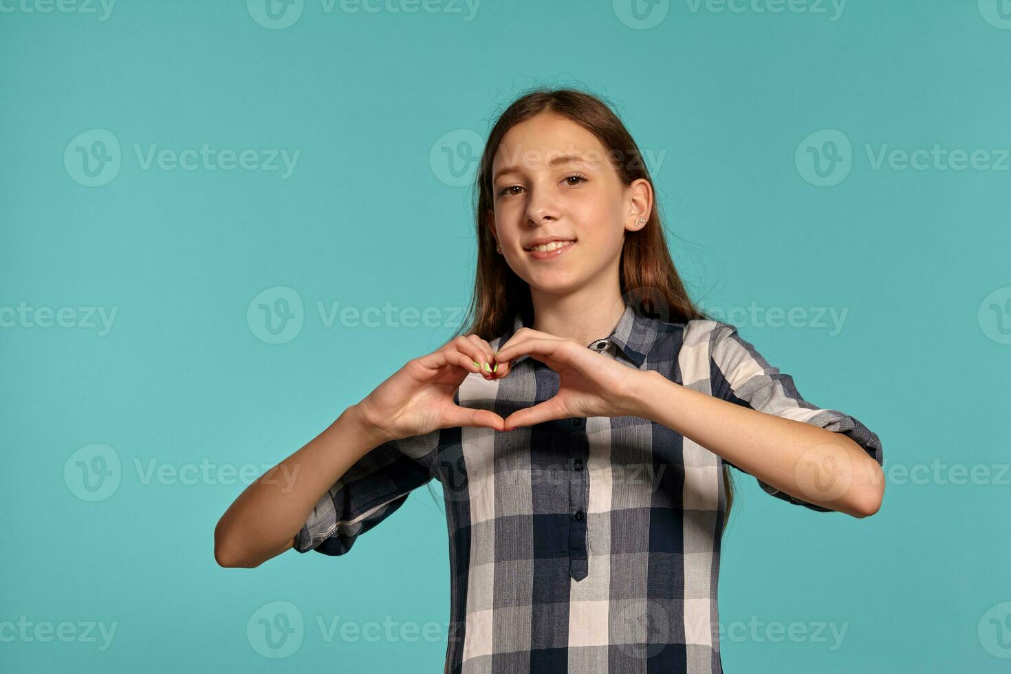 bellissimo adolescenziale ragazza nel un' casuale scacchi camicia è in posa contro un' blu studio sfondo. foto