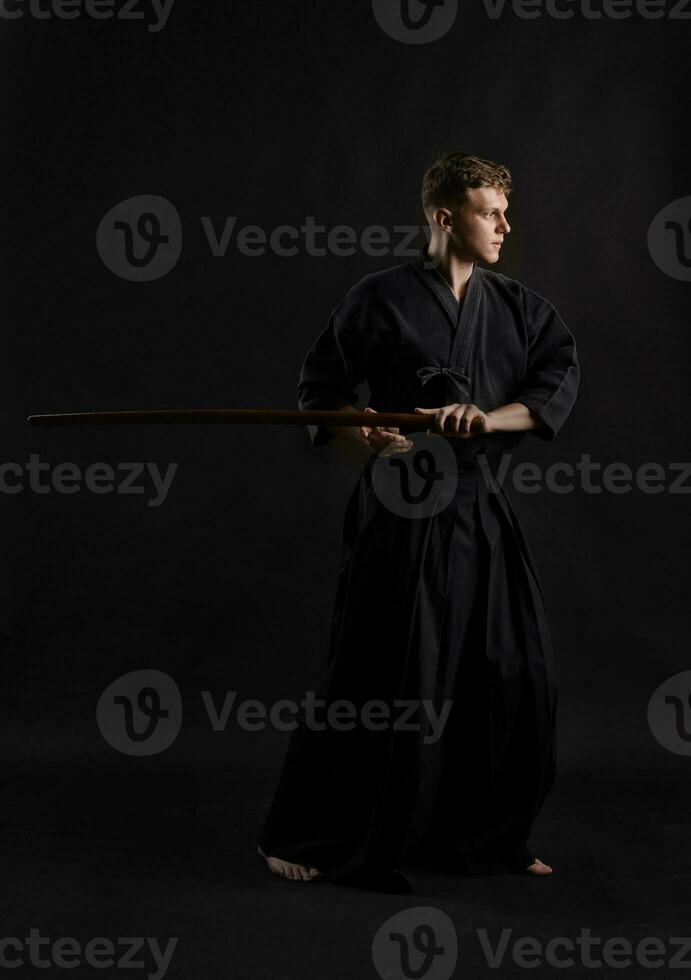 kendo guru indossare nel un' tradizionale giapponese chimono è praticante marziale arte con il shinai bambù spada contro un' nero studio sfondo. foto