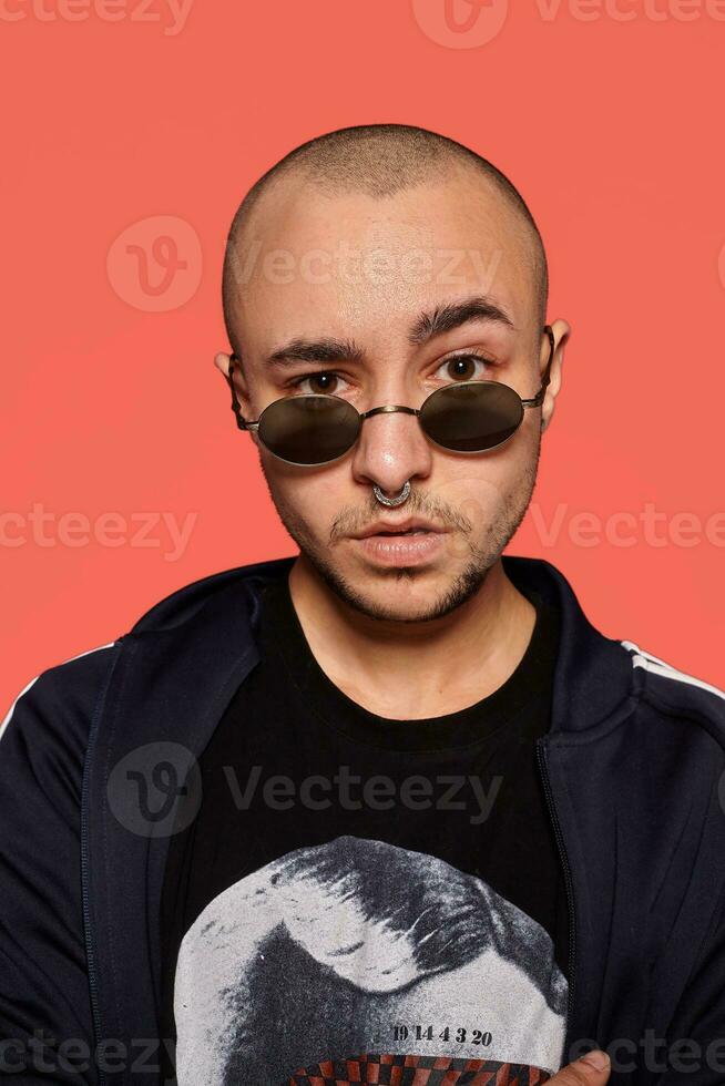 studio tiro di un' giovane tatuato Calvo uomo in posa contro un' rosa sfondo. anni 90 stile. foto