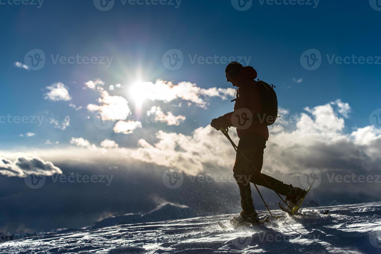 uomo che cammina nella neve con le racchette da neve foto