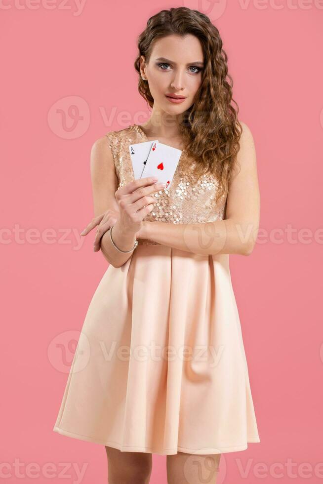 giovane bellissimo donna Tenere il vincente combinazione di poker carte su rosa sfondo. Due assi foto