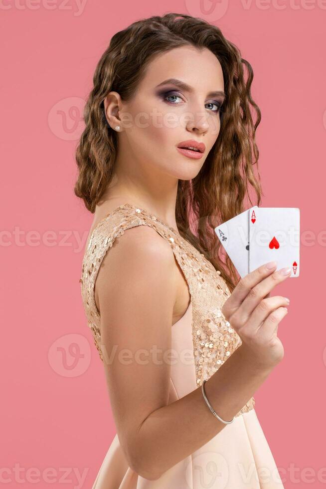 giovane bellissimo donna Tenere il vincente combinazione di poker carte su rosa sfondo. Due assi foto