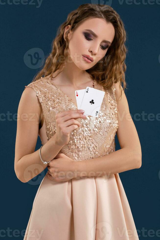 giovane bellissimo donna Tenere il vincente combinazione di poker carte su buio blu sfondo. Due assi foto