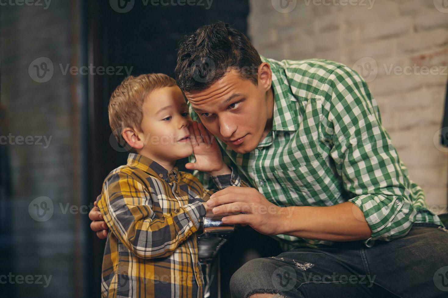 giovane bello padre e il suo poco elegante figlio a barbiere in attesa per barbiere foto