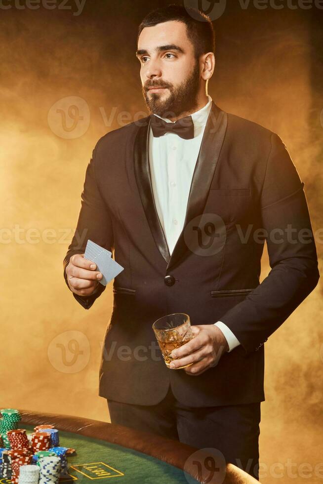 un' giovane uomo nel un' attività commerciale completo da uomo in piedi vicino poker tavolo. uomo scommesse. foto