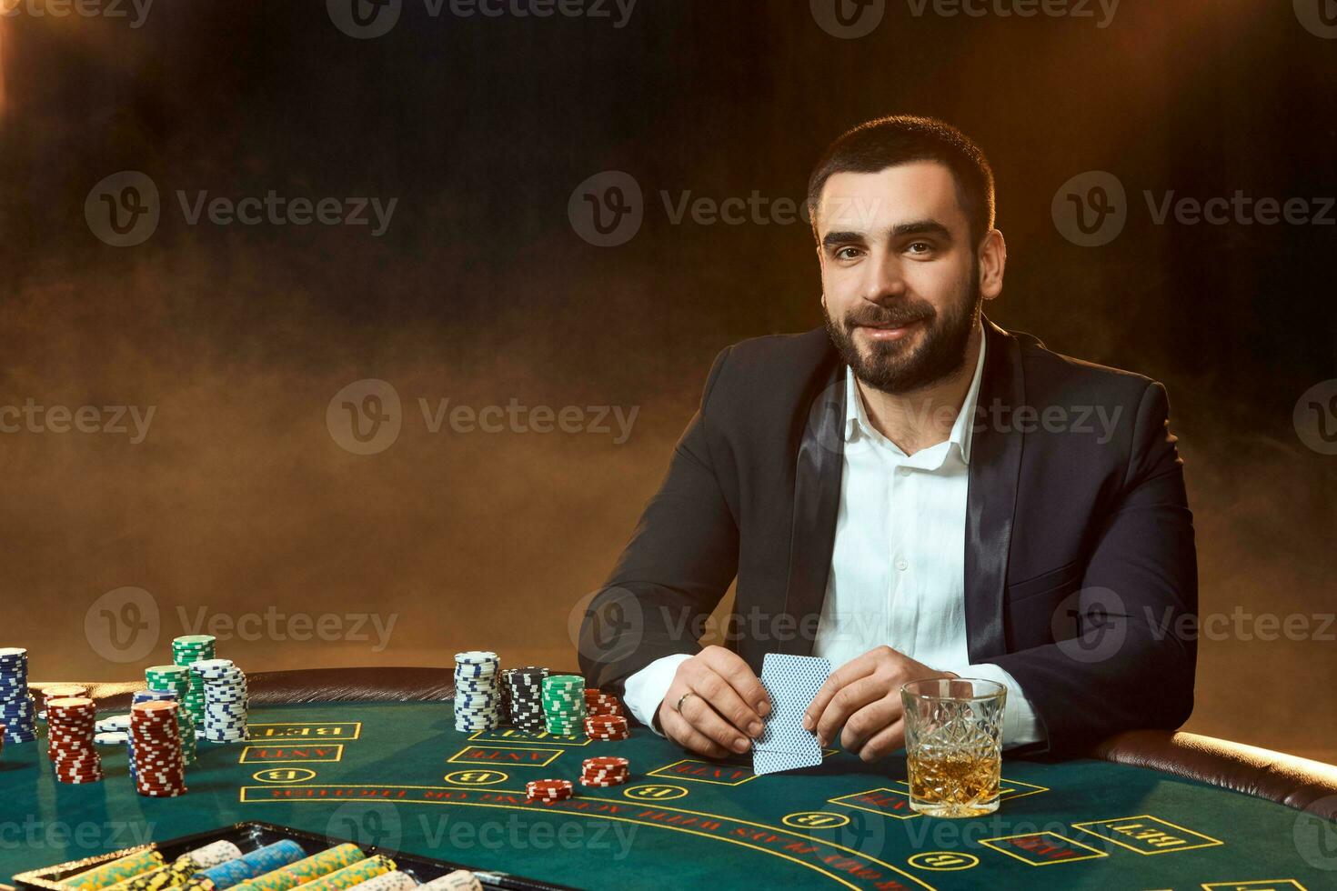 un' giovane uomo nel un' attività commerciale completo da uomo seduta a il poker tavolo. uomo scommesse. il giocatore a il gioco tavolo giocando carte. foto