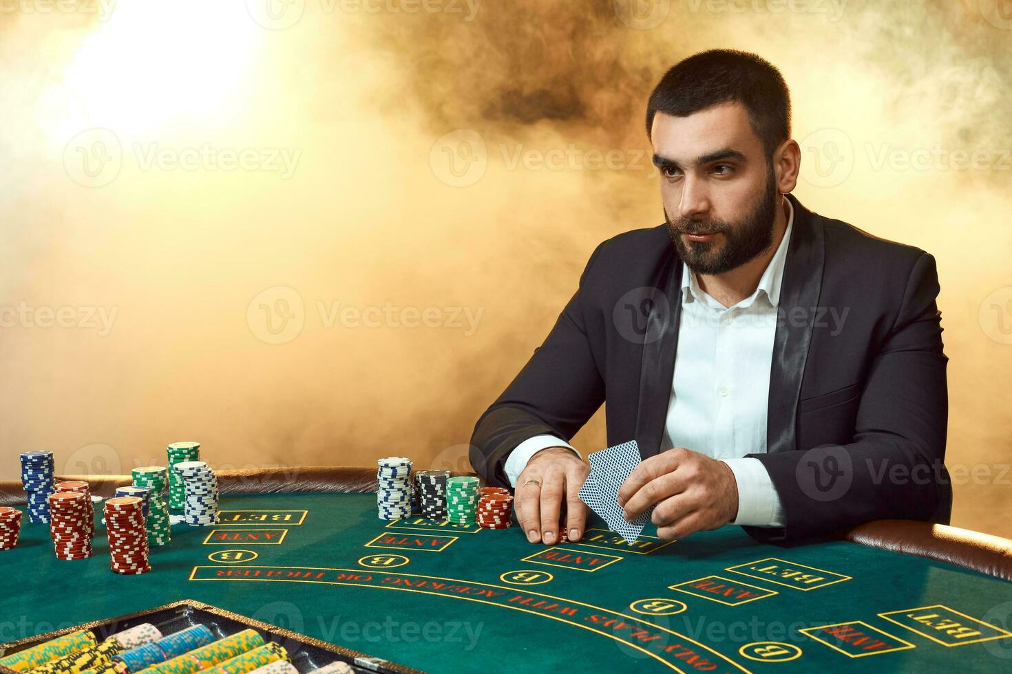 un' giovane uomo nel un' attività commerciale completo da uomo seduta a il poker tavolo. uomo scommesse. il giocatore a il gioco tavolo giocando carte. foto