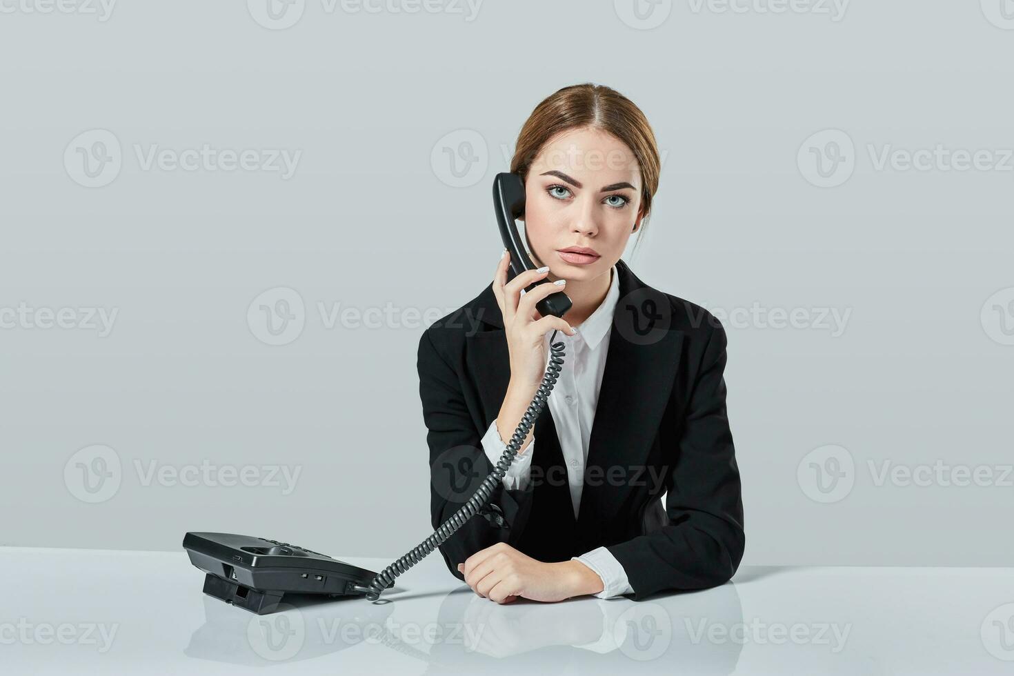 attraente dai capelli scuri donna vestito nel un' nero completo da uomo è seduta a tavolo nel un ufficio. foto