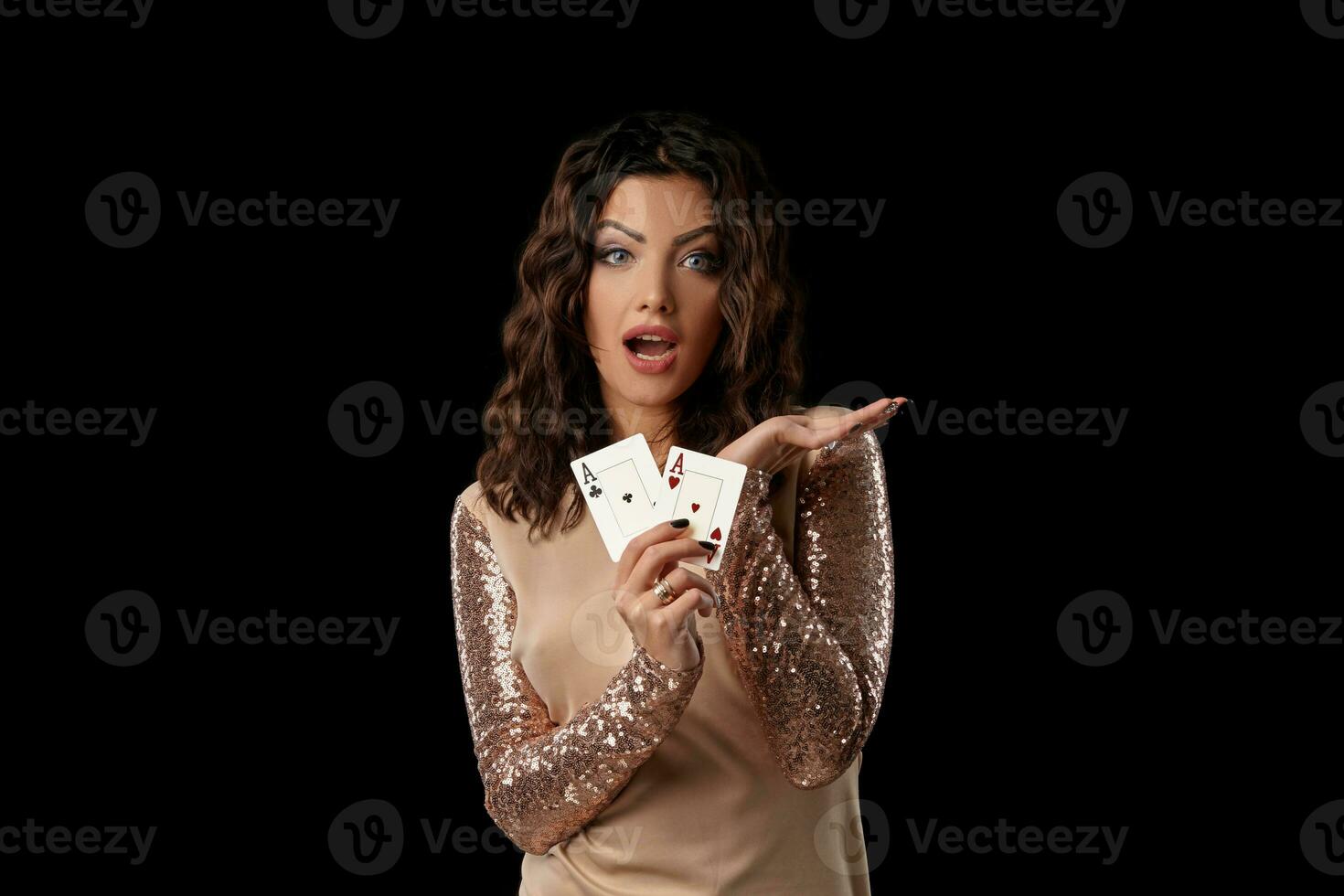 brunetta ragazza indossare brillante vestito in posa Tenere Due giocando carte nel sua mano in piedi contro nero studio sfondo. casinò, poker. avvicinamento. foto