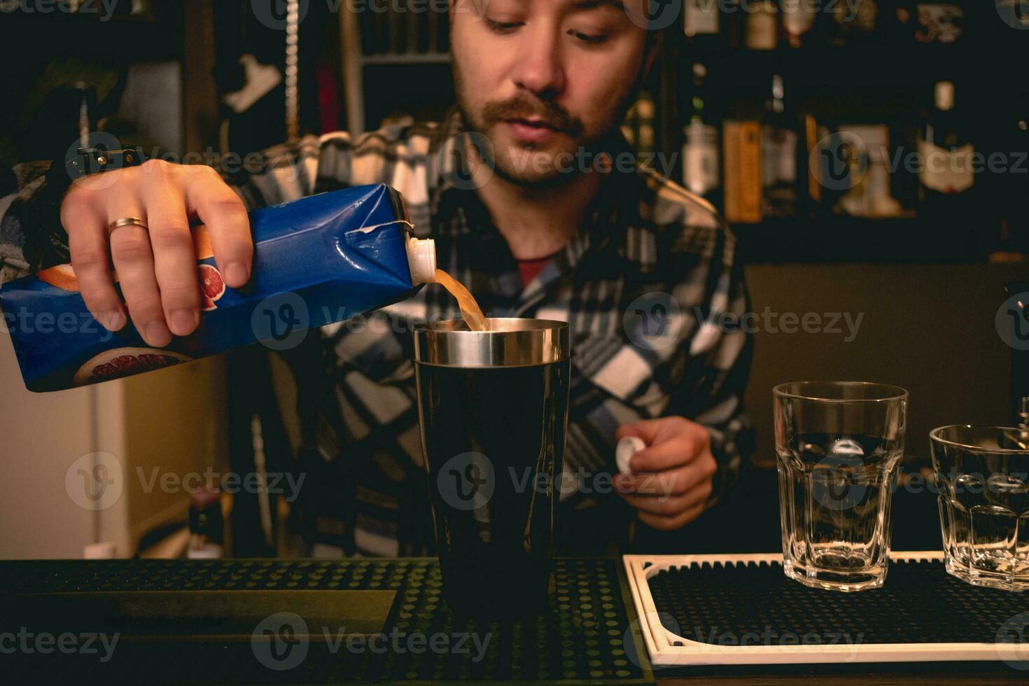 barbuto barista scrosciante arancia succo a partire dal scatola di cartone per shaker, preparazione cocktail foto