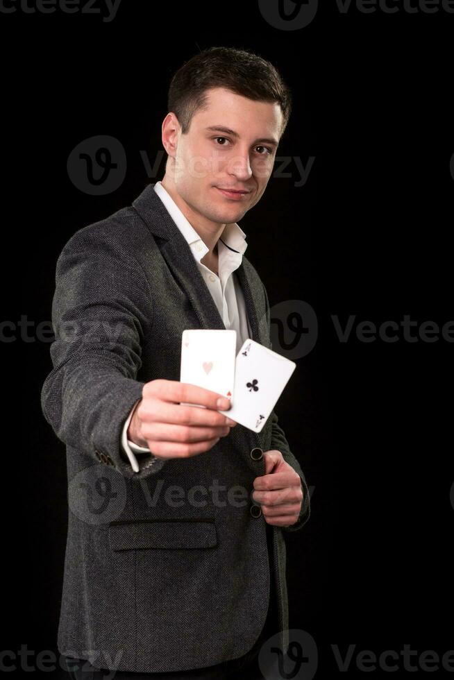 giovane caucasico uomo indossare completo da uomo Tenere Due assi nel il suo mano su nero sfondo. gioco d'azzardo concetto. casinò foto