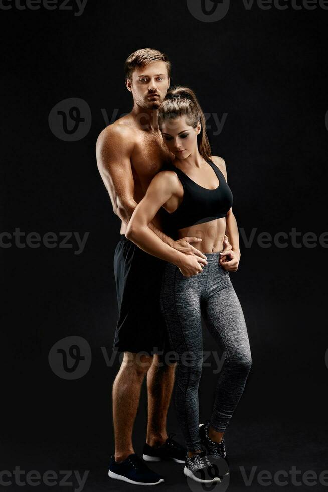 sport, fitness, allenarsi concetto. in forma coppia, forte muscolare uomo e sottile donna in posa su un' nero sfondo foto