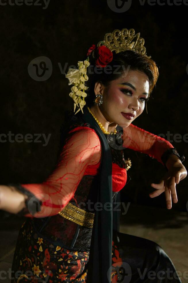 vicino su di un indonesiano donna nel un' balinese ballerino costume in posa molto meravigliosamente a notte foto