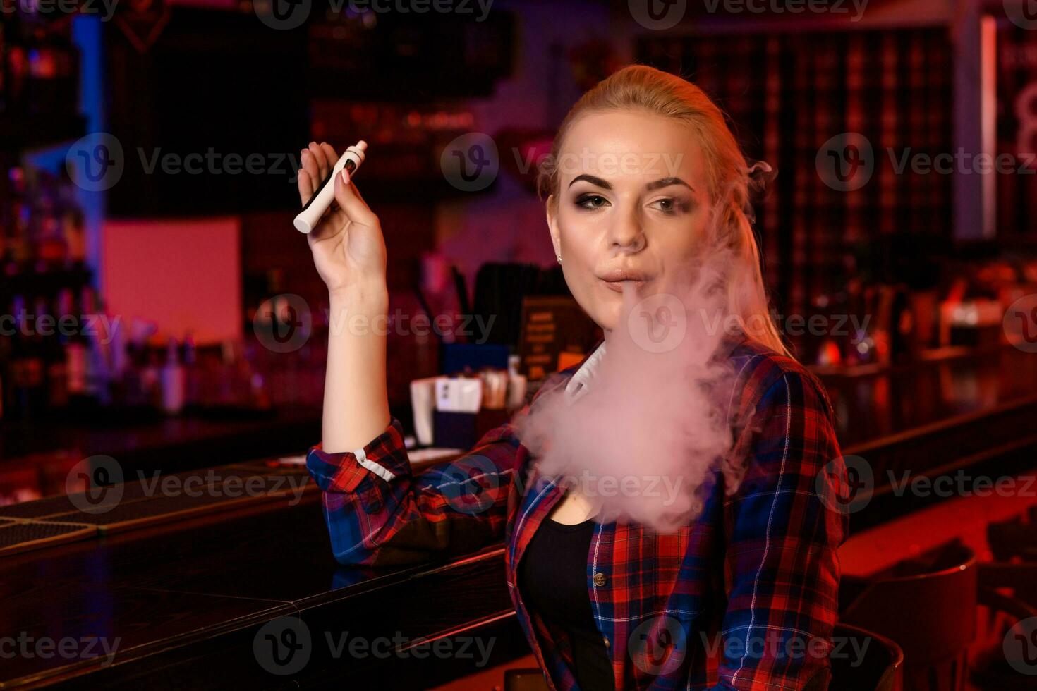 giovane bella donna Fumo un elettronico sigaretta a il Vape bar foto