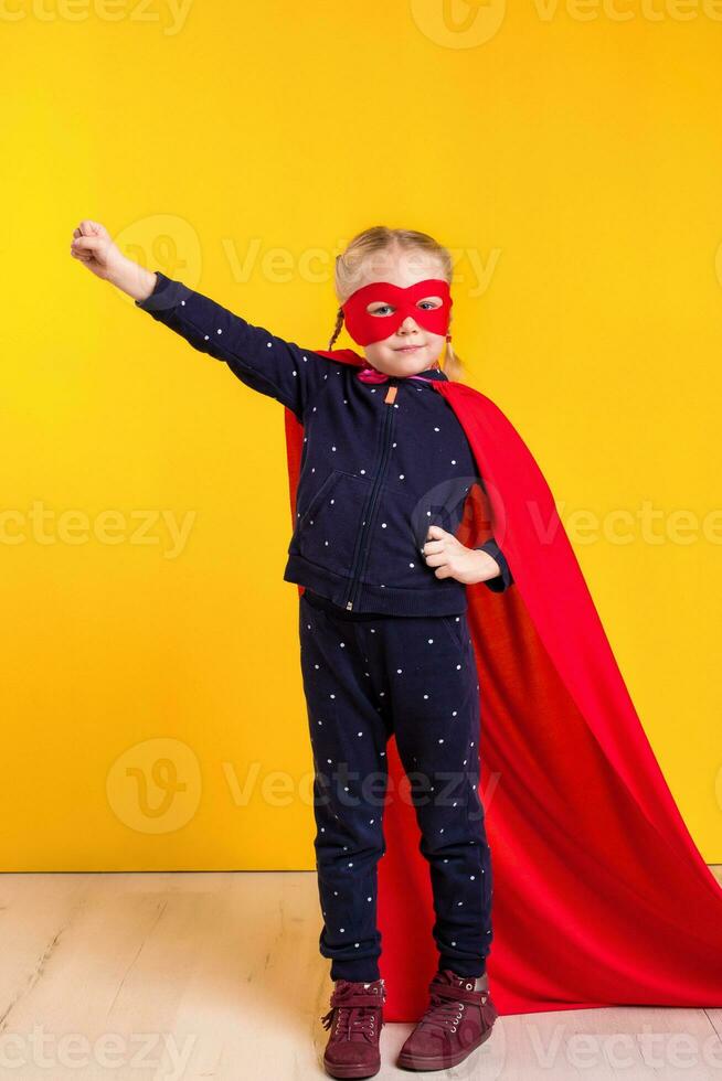 divertente poco energia supereroe bambino ragazza nel un' rosso impermeabile e un' maschera. supereroe concetto. foto