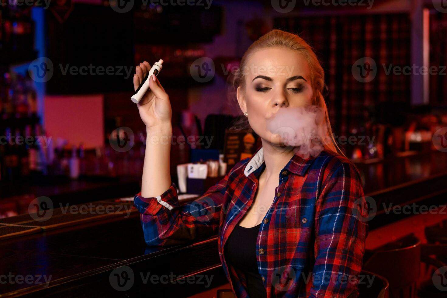 giovane bella donna Fumo un elettronico sigaretta a il Vape bar foto