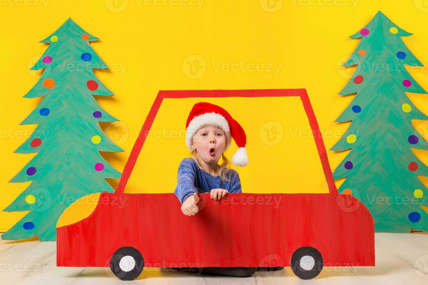 bambino con Natale cappello guida un' auto fatto di cartone. Natale concetto. nuovo anni vacanze. foto