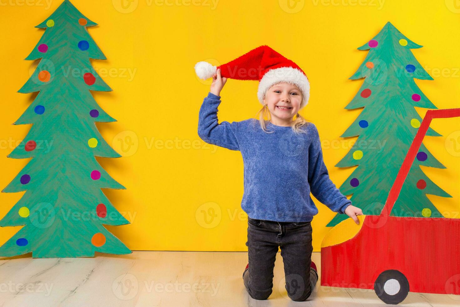 bambino con Natale cappello guida un' auto fatto di cartone. Natale concetto. nuovo anni vacanze. foto